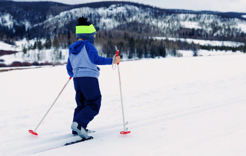Dziecko na nartach. W tle ośnieżone góry.
